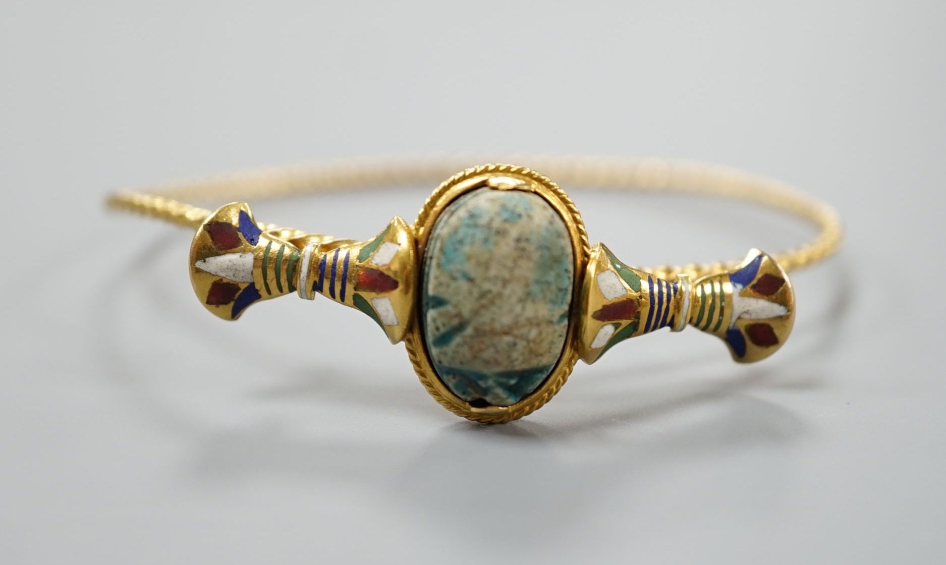A late 19th/early 20th century yellow metal, polychrome enamel and scarab set hinged bangle, interior diameter 58mm, gross weight 11.7 grams.